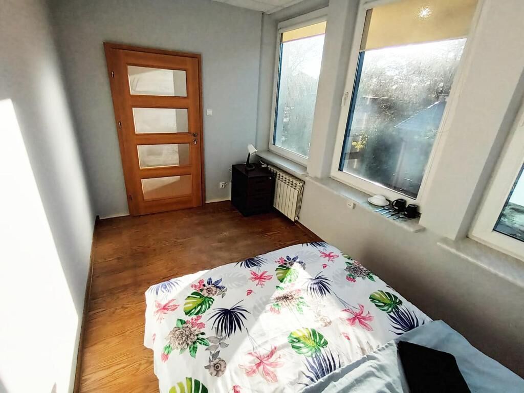Un dormitorio con puerta de madera, un radiador y una cama con colcha estampada.