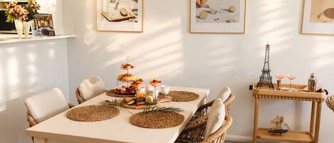 A dining area with a white table, wicker chairs, and a tray with drinks and snacks.