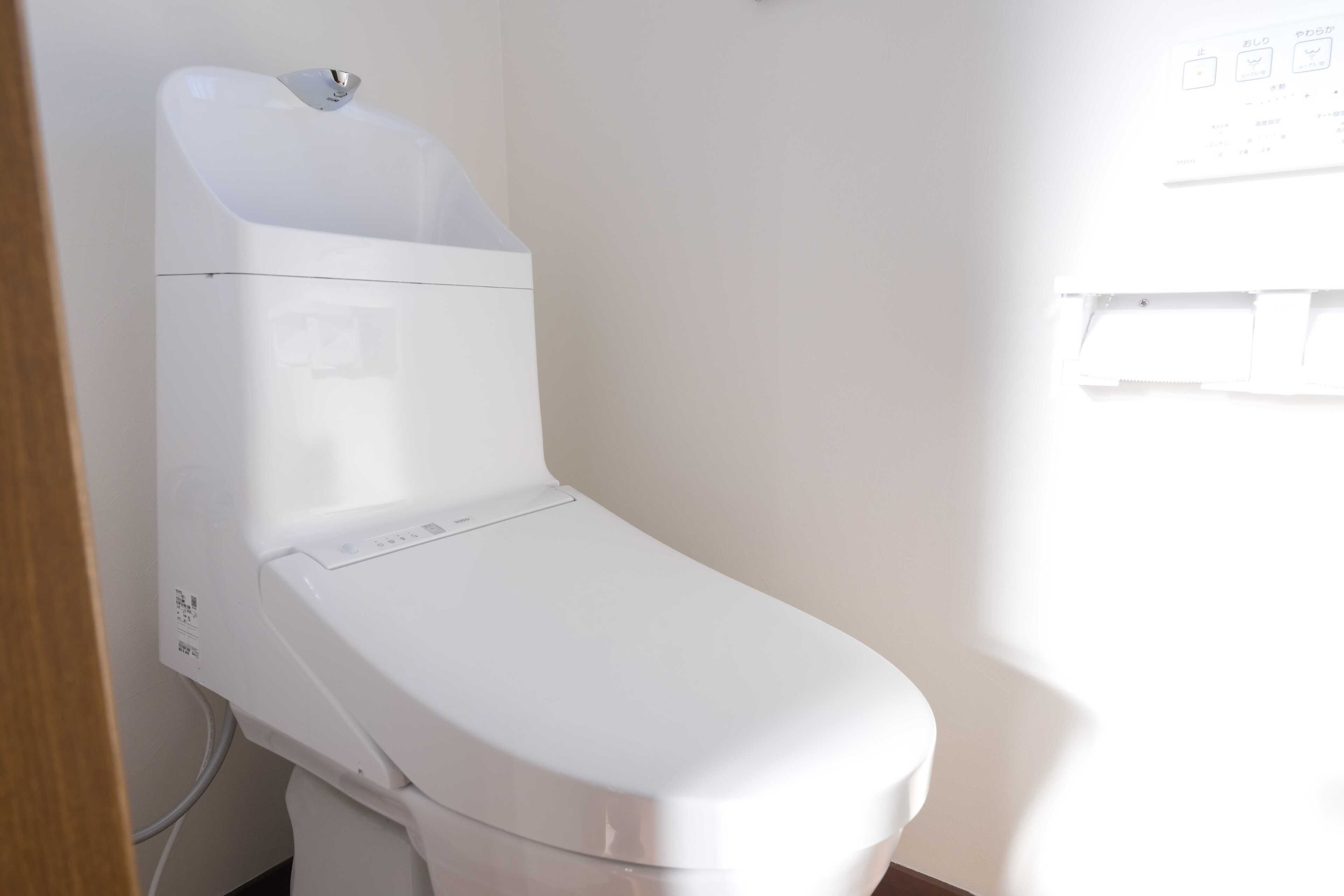 A white toilet with a control panel and a wall-mounted sink.