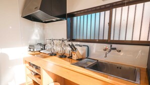 Eine moderne Küche mit Spüle aus Edelstahl, einer Holzarbeitsplatte und einem Fenster mit Milchglas.