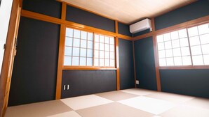 Ein Zimmer mit Tatami-Boden, Schiebetüren und Deckenventilator.