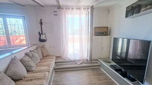 A living room with a sofa, TV, guitar, and a window with curtains. - Stilvolles Landhaus an der Algarve by Interhome (Algoz)