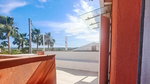 A balcony with a view of palm trees and a building in the distance. - Stilvolles Landhaus an der Algarve by Interhome (Algoz)