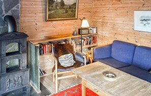 A cozy living room with a fireplace, a blue sofa, a wooden table, and a bookshelf filled with books. - Awesome home in Tjørhom (Tjørhom)