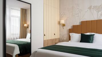 Habitación de hotel con cama, espejo, armario y pared con papel tapiz floral.