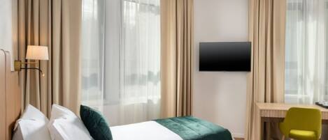 A hotel room with two beds, a desk, a chair, and a TV on the wall.