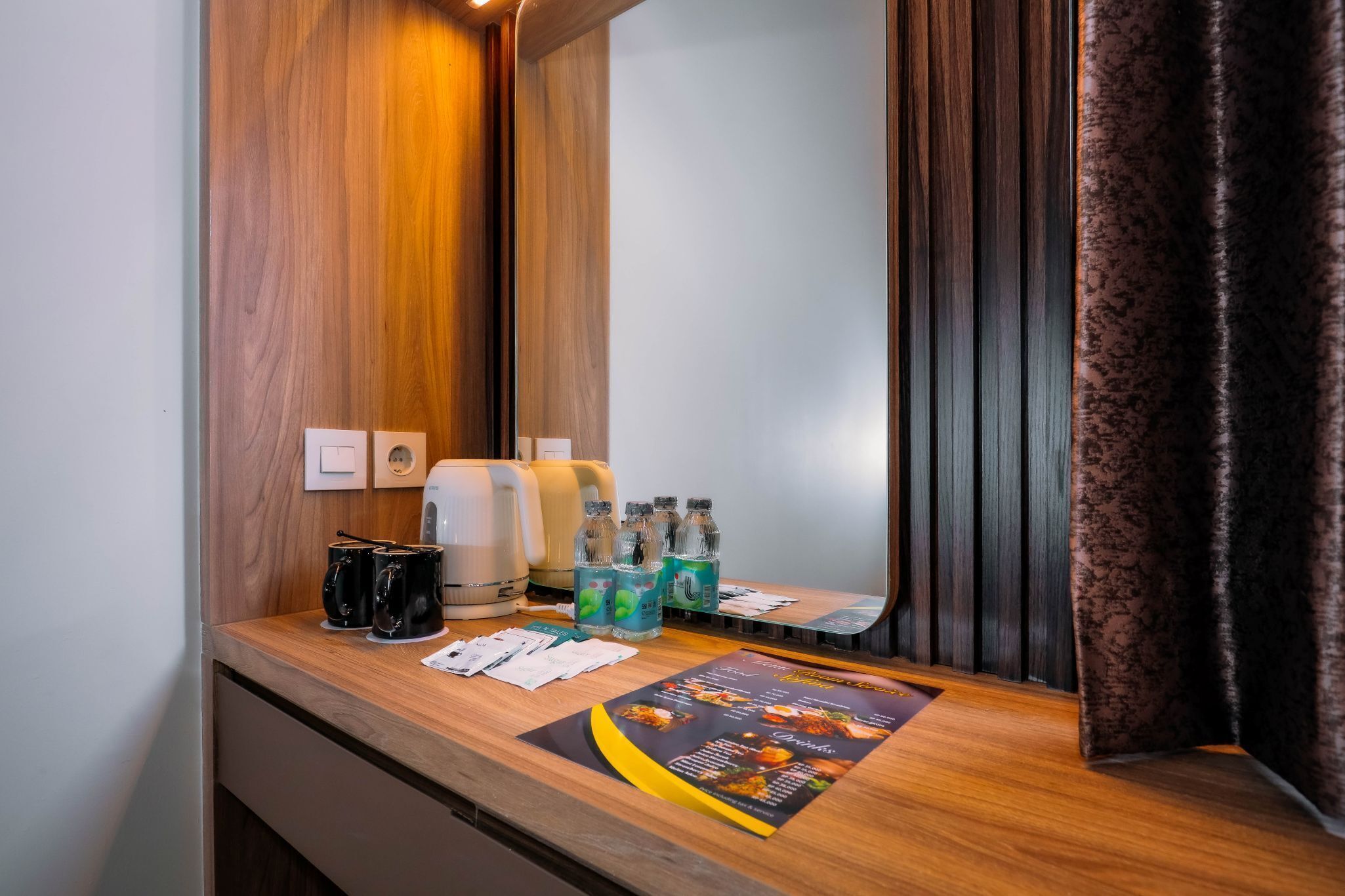 Um balcão de recepção de hotel com bancada de madeira, uma máquina de café, água engarrafada e um menu.