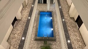 A pool with a patterned floor, surrounded by walls and columns. - Front One Hotel Mesir Surabaya (Surabaya)