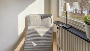 En enkeltseng i et rum med et vindue, en radiator og en lampe på vindueskarmen.