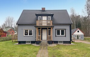Une maison à deux étages avec un balcon, une porte d’entrée et un petit porche.