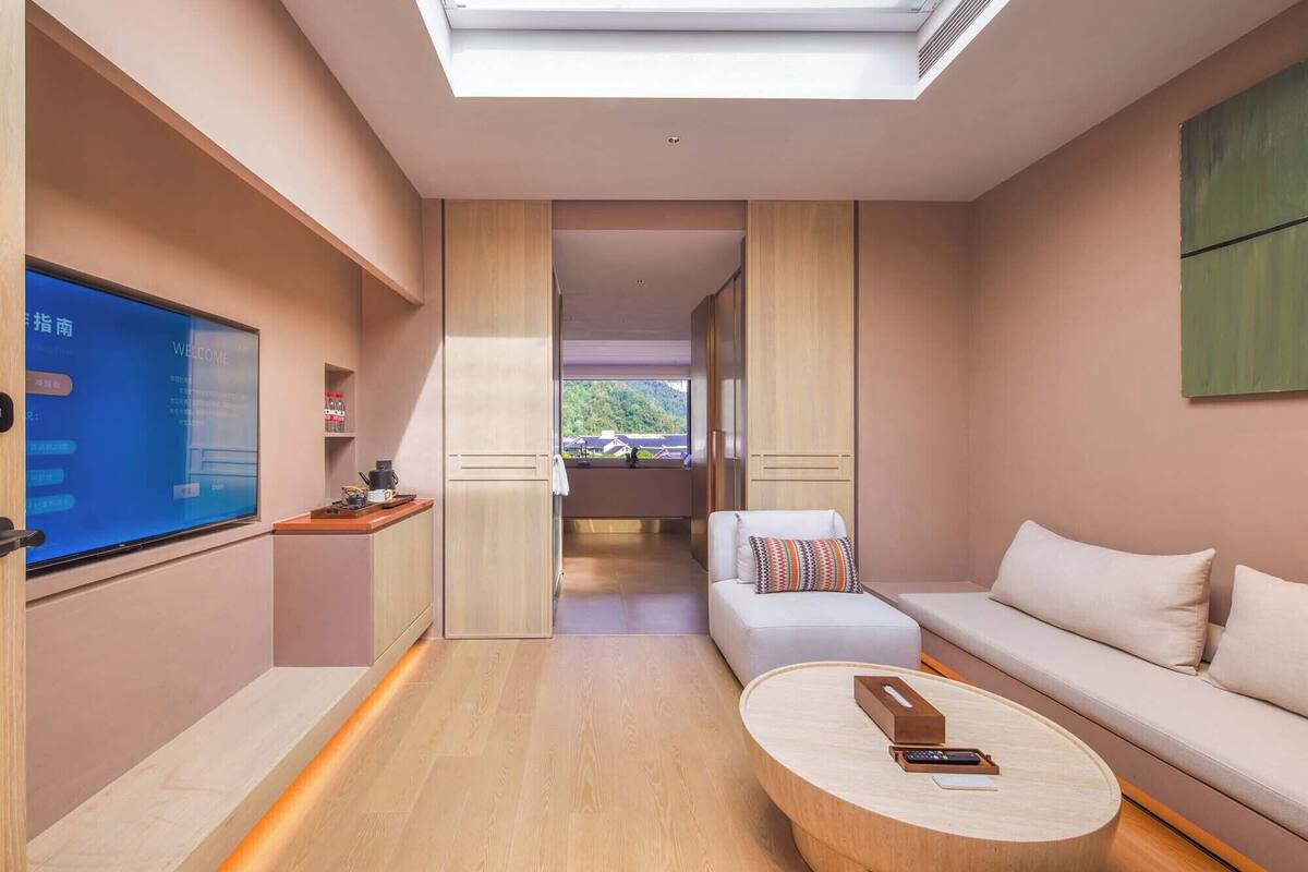 Ett modernt hotellrum med en stor TV, en soffa, ett soffbord och utsikt över omgivningarna.