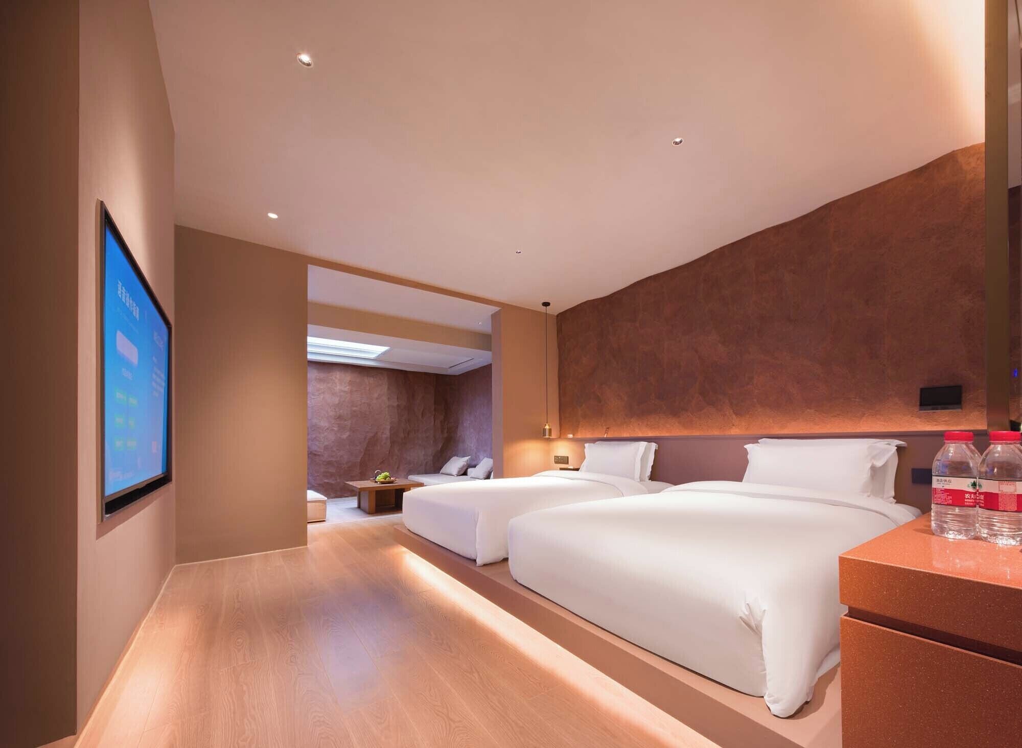 Une chambre d’hôtel avec deux lits, un bureau, une télévision et une vue sur le couloir.