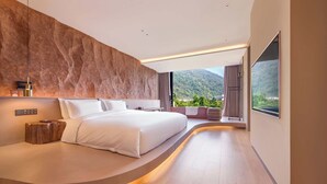A modern bedroom with a curved bed, a large window with a mountain view, and a stone accent wall. - Zhangjiajie Shisuji Hotel - Zhangjiajie National Forest Park Avatar Scenic Area Branch (Zhangjiajie)
