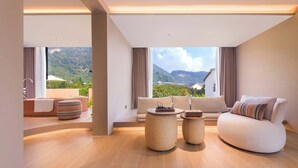 A modern living room with a sofa, two round tables, and a view of a mountainous landscape through large windows. - Zhangjiajie Shisuji Hotel - Zhangjiajie National Forest Park Avatar Scenic Area Branch (Zhangjiajie)