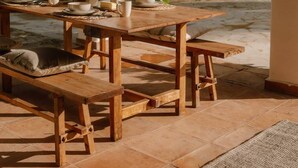 Una veranda esterna con tavolo e panche in legno, circondata da colonne bianche e un lanterne appesa.