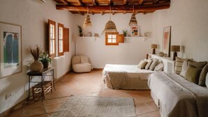Una stanza accogliente con soffitto in legno, un divano, un letto, una poltrona e lampade a sospensione.