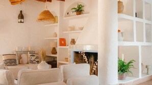 Un accogliente soggiorno con soffitto in legno, un divano bianco, uno sgabello di legno e un camino.