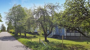 Ein Wohngebiet mit einer gepflasterten Straße, einem blauen Haus mit weißem Zaun und Bäumen.