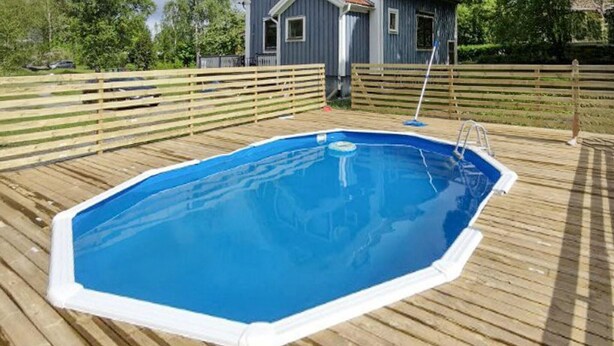 Ein rechteckiger Pool über dem Boden mit einer Leiter an einer Seite, umgeben von einer Holzterrasse.