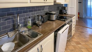 Eine Küche mit Spüle aus Edelstahl, Kaffeemaschine und Toaster auf der Arbeitsplatte.