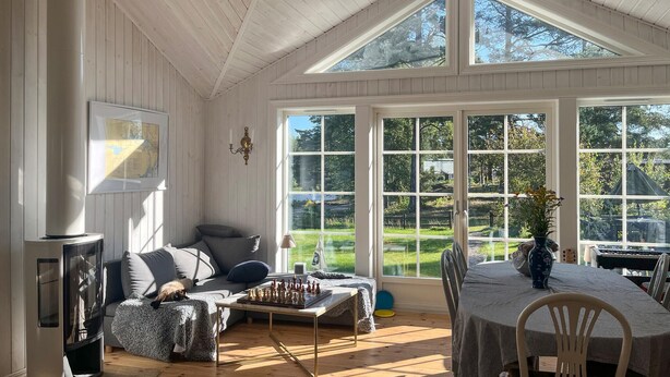 A spacious room with a high ceiling, large windows, a chessboard, and a cozy seating area.
