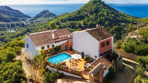 Una villa con piscina, tejas de cerámica y vistas al mar y a las montañas.