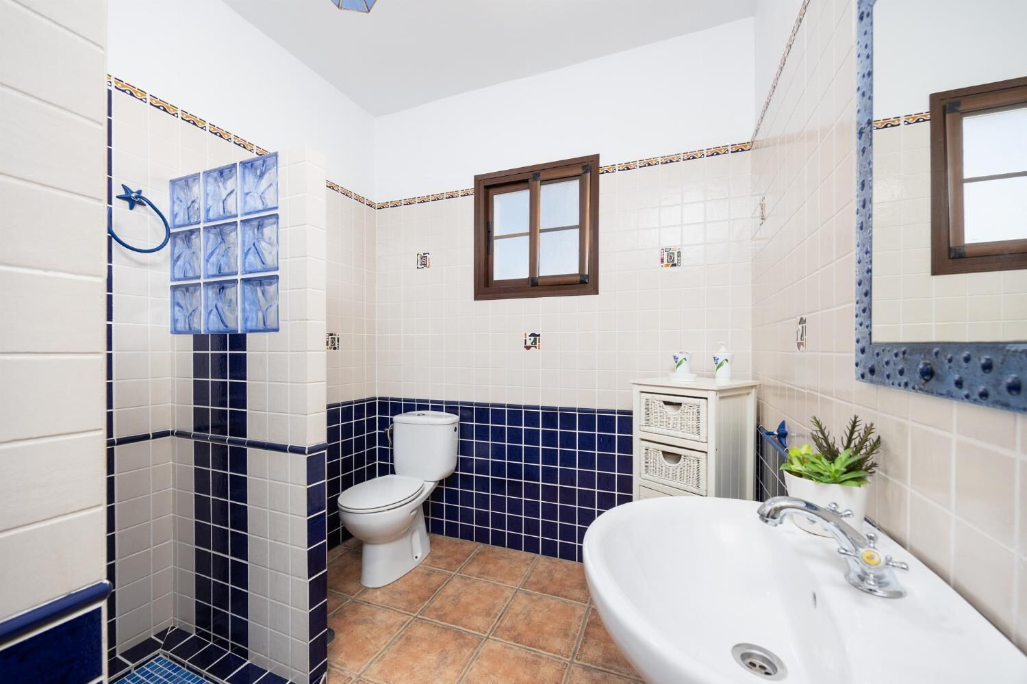 A bathroom with a white toilet, a sink, and a shower area.