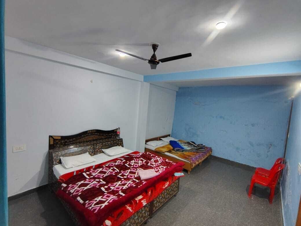A room with two beds, a ceiling fan, and a red chair.