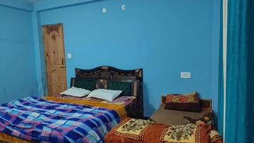 Un dormitorio con dos camas, una puerta de madera y una pared azul.