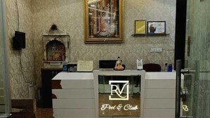A reception area with a marble floor, a reception desk with a 'Pool & Club' sign, a framed artwork above the desk, and a 'OFF' sign on the wall.