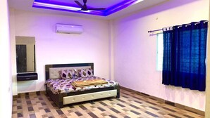 A bedroom with a bed, a ceiling fan, an air conditioning unit, a window with curtains, and a mirror.