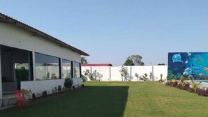 A residential property with a well-maintained lawn, a white building with large windows, and a mural of marine life on the adjacent wall.