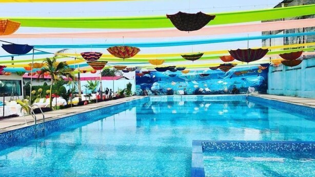 A swimming pool with colorful umbrellas and a mural of fish on the walls.