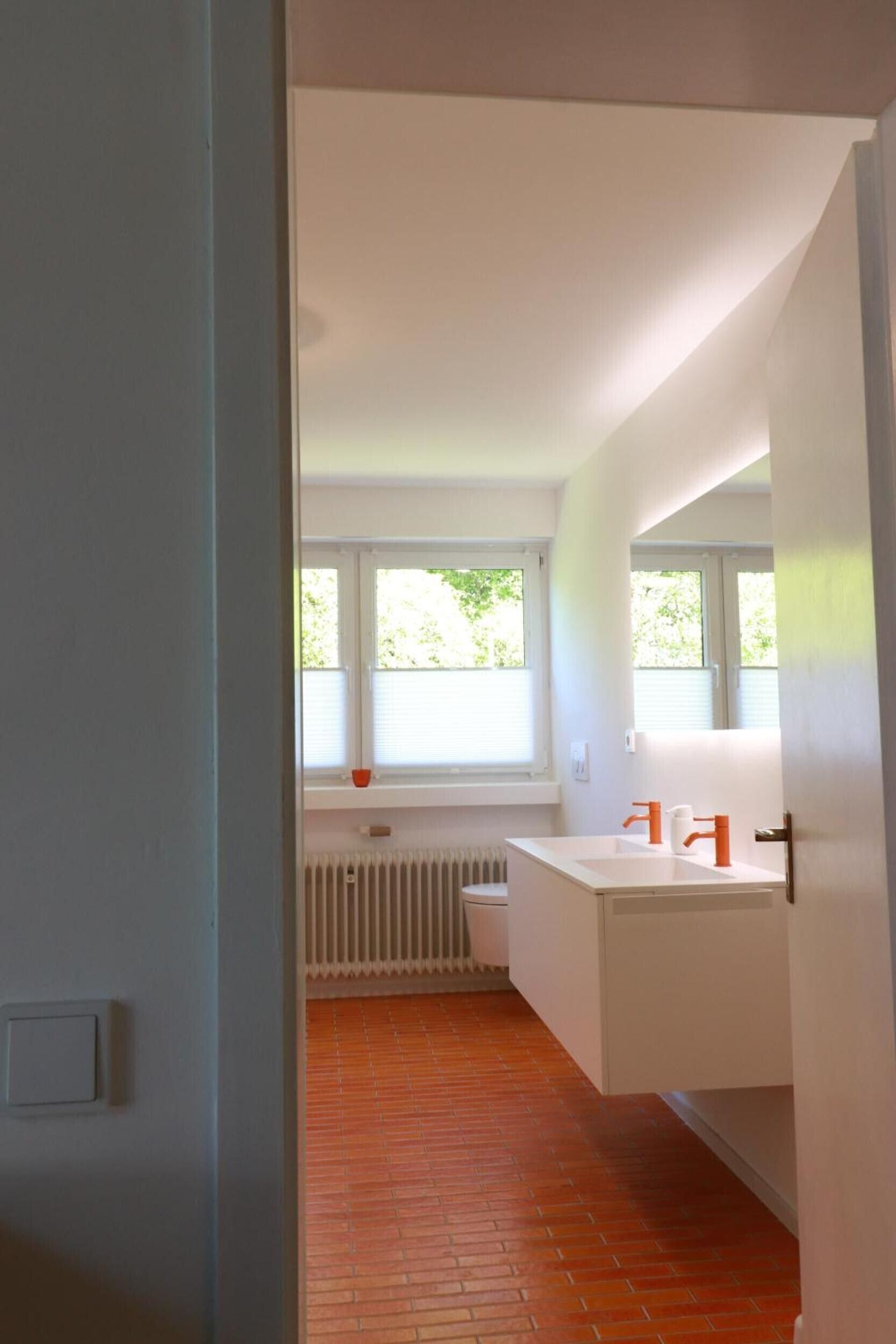 Ein modernes Badezimmer mit einem weißen Waschbecken, einer Toilette und einem Fenster.