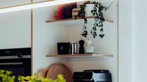 Une cuisine équipée d’un four à micro-ondes, d’une machine à café et d’une étagère avec des livres et une plante.