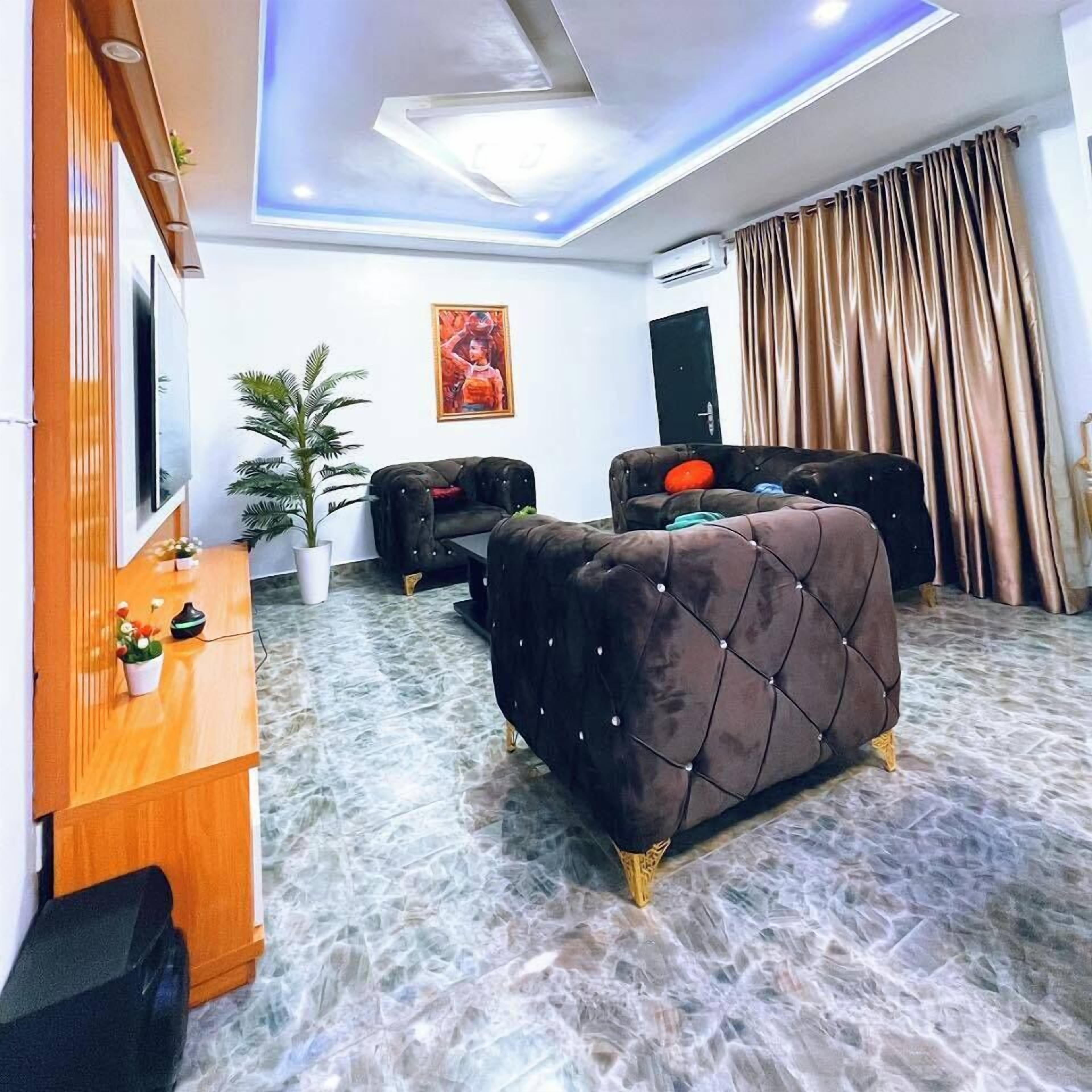 Ein modernes Wohnzimmer mit Marmorboden, einem großen braunen Sofa, einem Holzschrank, einem Fernseher und einem Bild an der Wand.