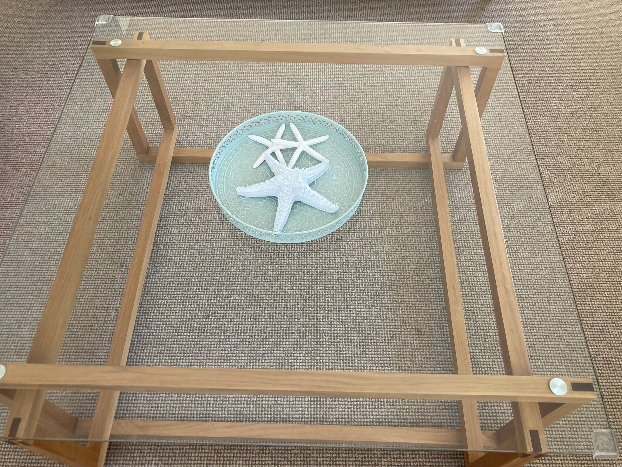 A square wooden stand with a glass top and a decorative starfish on it.