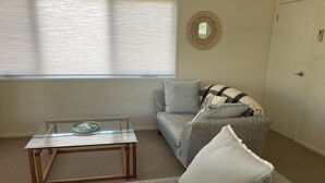 A living room with a glass coffee table, a sofa, and a striped throw blanket. - 20 Bradley (Coles Bay)