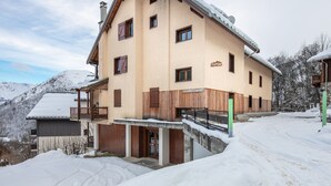 En byggnad med flera våningar, ett sluttande tak, träbalkonger och en skylt som visar att det är ett skidområde.