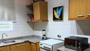 A kitchen with wooden cabinets, a built-in oven, a microwave, and a blender on the countertop. - Lavish Apartment (Abuja)
