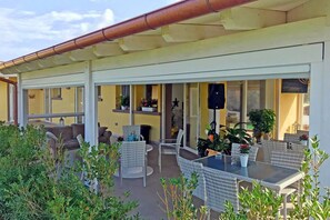 En udendørs patio med fletmøbler, et bord og plantekrukker.