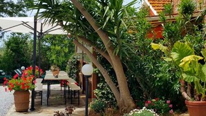 Eine Terrasse mit Tisch und Stühlen, umgeben von Blumentöpfen und Blumen.