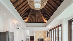 Un comedor moderno con una mesa de madera y sillas tejidas, un techo con diseño de listones de madera y un ventanal grande a la derecha.