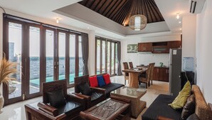 Amplia sala de estar con un gran ventanal con vista a un cuerpo de agua, zona de cocina y comedor.