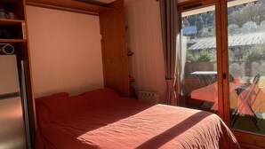 A bedroom with a bed, a wardrobe, a radiator, and a window with curtains. - Nice Apt for 4 pers mountain view (Morillon)