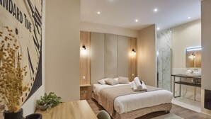 A modern bedroom with a bed, bedside tables, a desk, a potted plant, and a bathroom with a mirror and sink. - Sublime apartment in the heart of Paris 10 people (Paris)