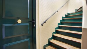 A staircase with wooden steps and a metal handrail, leading to a door with a brass doorknob. - Charming  Duplex Le Marais/Beaubourg (Paris)