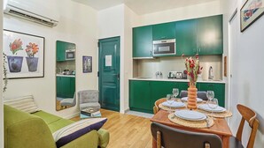 A compact living space with a dining area, kitchenette, and a green sofa. - Charming  Duplex Le Marais/Beaubourg (Paris)