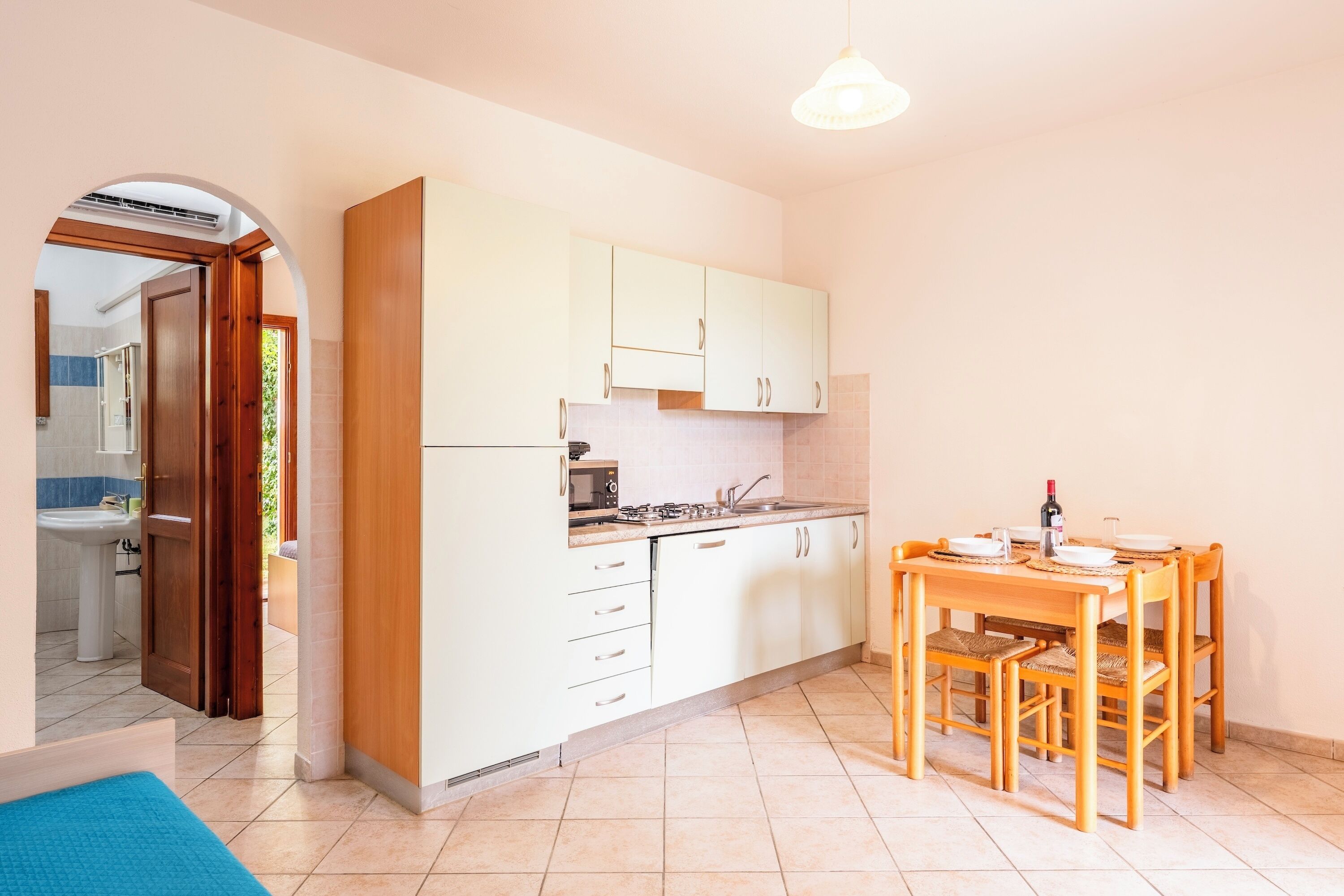 A compact kitchen with white cabinets, a dining table with chairs, and a visible sink.