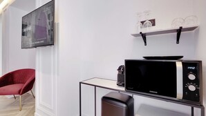 Een moderne keuken met een Samsung magnetron, een rode stoel en een tv met daarop de tekst 'Geniet in Parijs'.
